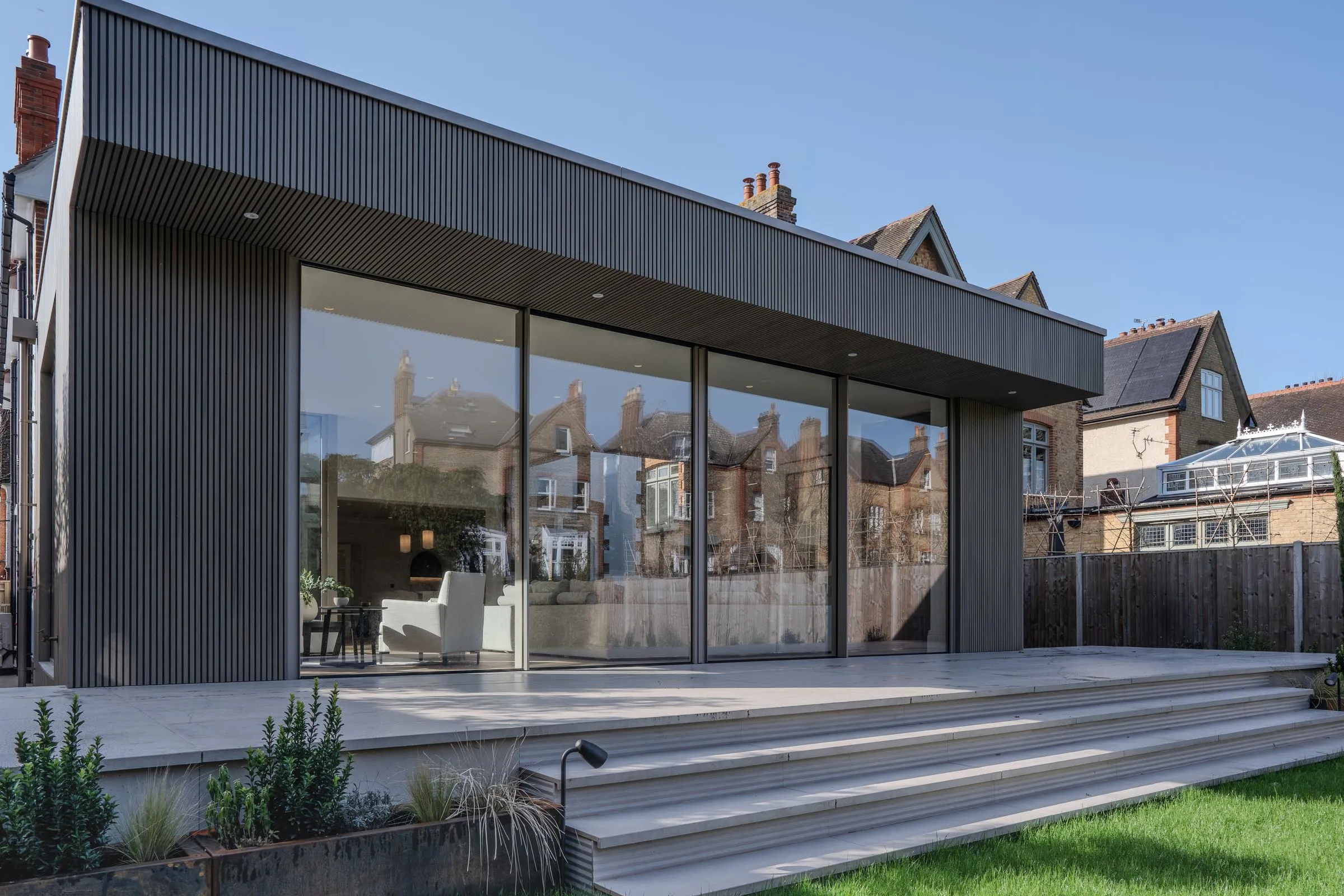 Sliding doors along a timber-clad extension, from the terrace