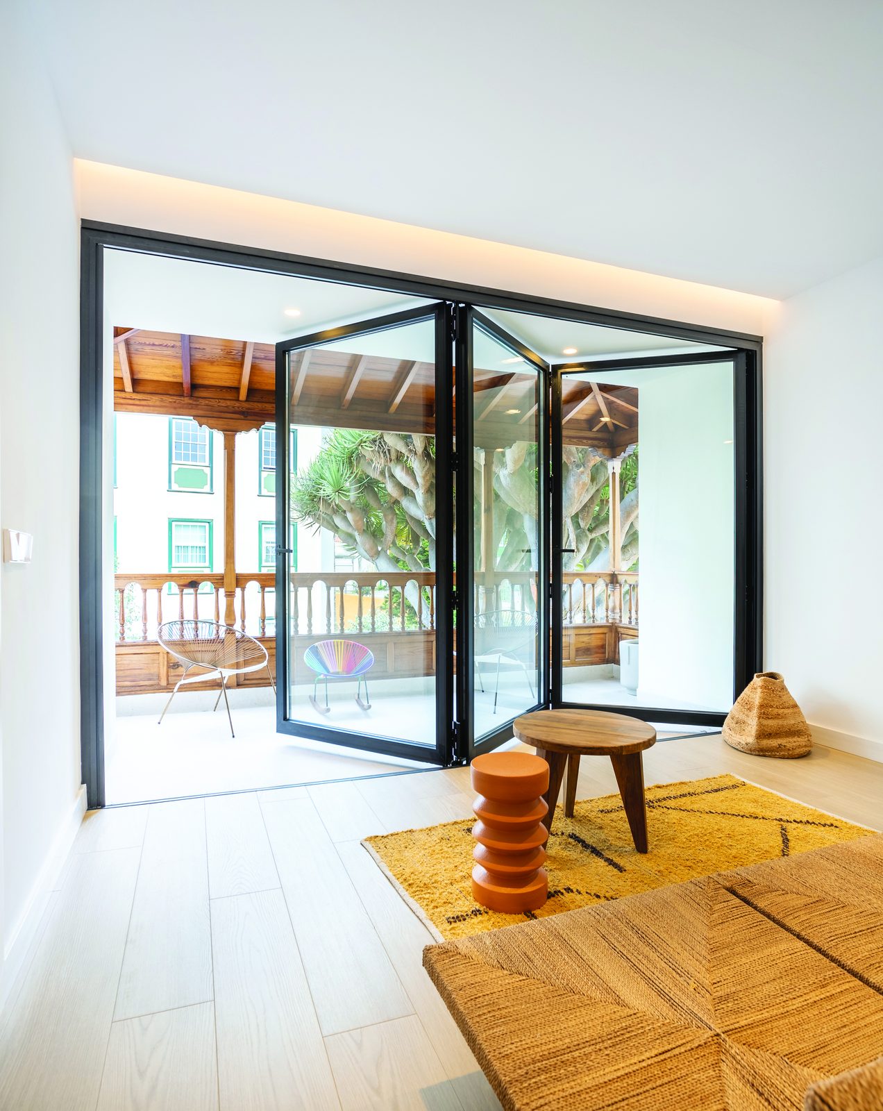 Slim black bifold doors folding back in a bright living room