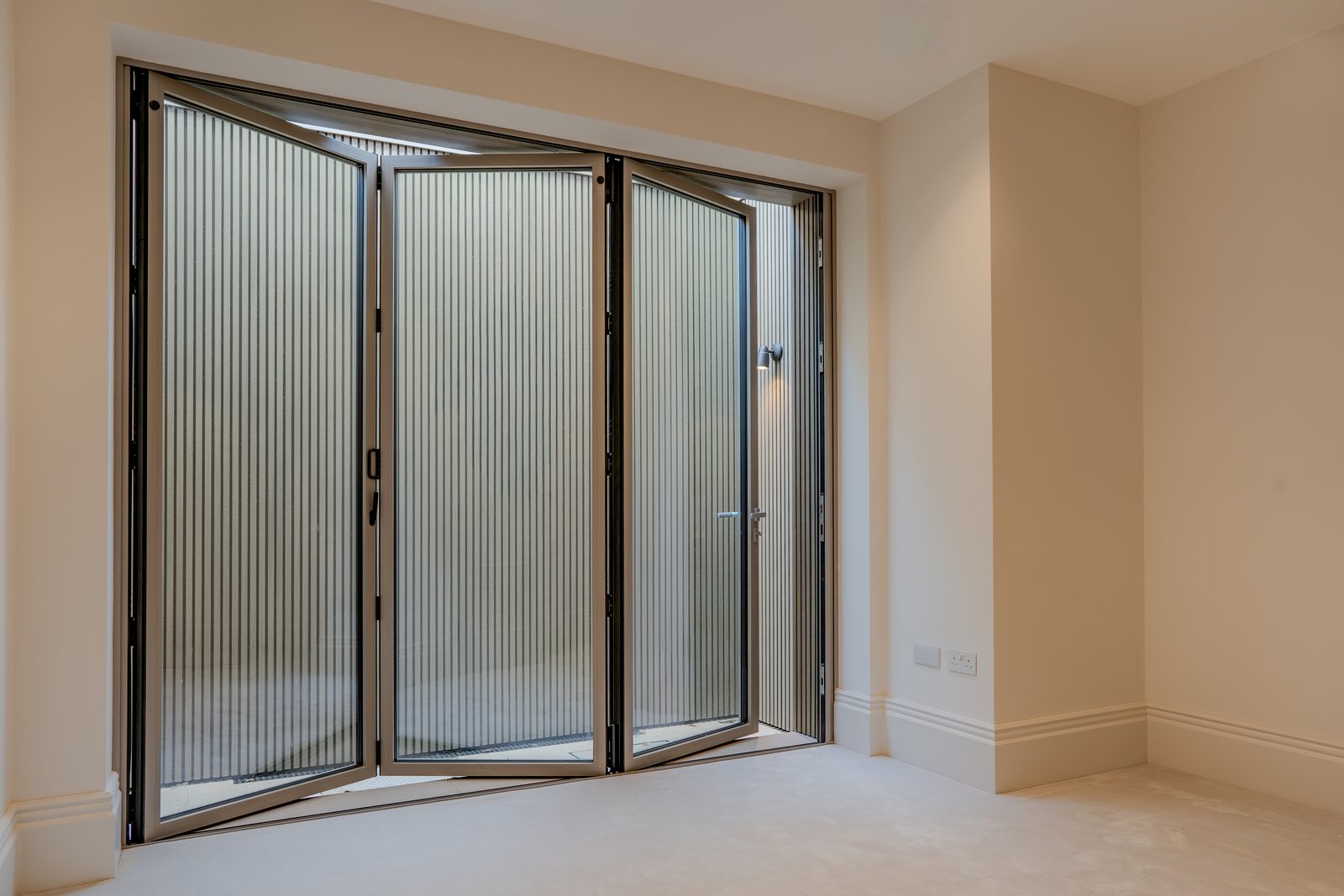 Three-panel bifold door part folded, bronze finish, seen from inside