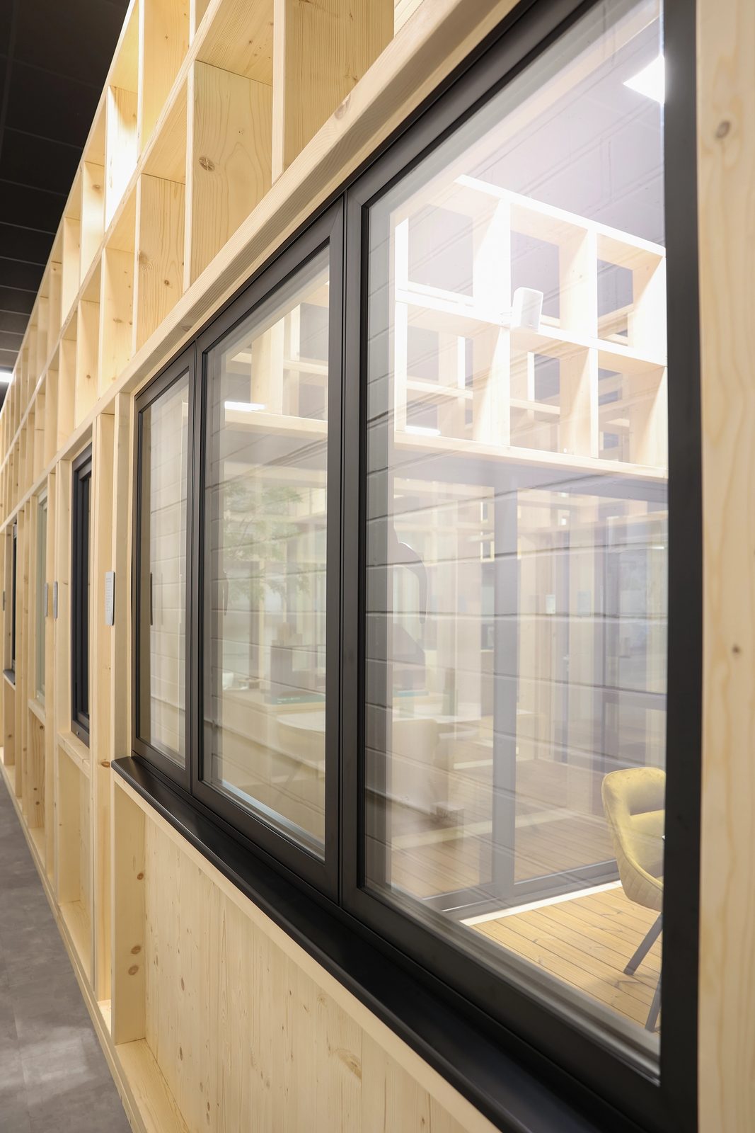 Flush aluminium casement windows in a timber-lined room